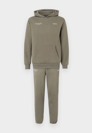 Conjunto de sweatshirt e calças de fato em verde oliva. O capuz tem um bolso frontal e detalhes em texto branco. Tecido suave, corte descontraído e punhos canelados.