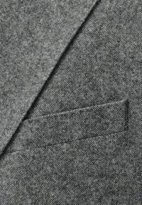 Gray blazer fabric with a textured pattern, featuring a visible chest pocket and tailored lapel, indicating a formal design.