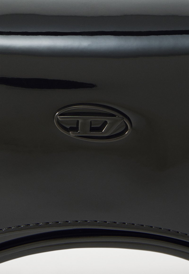 Borsa a mano nera lucida con un grande logo ovale e una trama liscia e sinuosa; dettagli di cucitura minimi lungo il bordo.