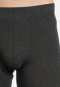 Leggings gris avec une texture lisse, une taille élastique et des coutures renforcées. Le tissu semble doux et légèrement extensible.