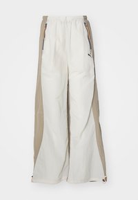 Pantalones ligeros blancos y beige con un acabado texturizado, que presentan una cintura elástica, bolsillos laterales y un pequeño logo negro.