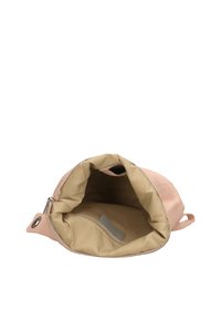 Rosa läderväska med ett mjukt, fodrat inre. Öppningen avslöjar en beige tygfoder och en liten grå bit material för etiketter.