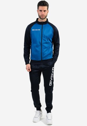 Giacca a tracolla blu e nera con chiusura a zip e logo, abbinata a pantaloni neri coordinati con scritte bianche. Realizzata in un tessuto morbido e resistente.