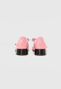 Sapatos de couro sintético rosa com bico arredondado, apresentando tacões quadrados pretos e tiras finas nos tornozelos. Textura suave sem padrões visíveis.