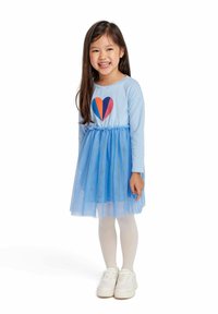 Blue dress with striped long sleeves, tulle skirt, and colorful heart design. White tights and shoes complete the outfit.