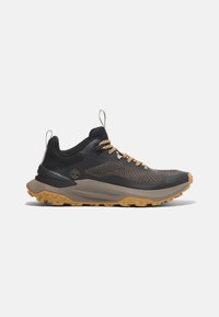 Zapatillas deportivas negras con una parte superior texturizada, acentos beis y suela robusta. Cuenta con un diseño de cordones y una lengüeta para facilitar su uso.