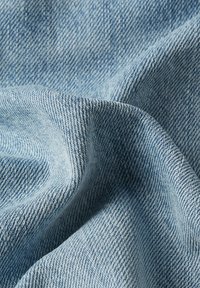 Tissu denim de culoare albastru deschis, cu un țesătură în diagonală, care prezintă o textură netedă și un model subtil diagonal. Aspect moale, flexibil și ușor drapat.