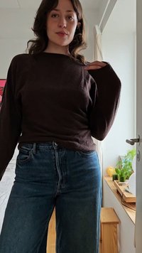 Bruine lange mouwen gebreide top gecombineerd met blauwe high-waisted jeans. De top heeft een relaxte pasvorm; de jeans hebben een klassiek vijf-pocket ontwerp.