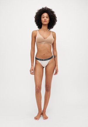 Bralet wireless bej cu bretele subțiri și o bandă texturată; thong crem asortat cu o talie logo neagră.