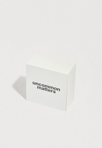 Valkoinen laatikko, jossa on mattapinta ja jommallakummalla sivulla paksulla mustalla tekstillä painettu "uncommon matters". Yksinkertainen, suorakulmainen muotoilu.