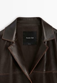 Bruine leren jas met een gekartelde kraag, voorzien van een zwarte voering en een rechthoekig label met het merk "Massimo Dutti".