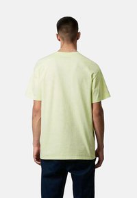 Camiseta de manga corta en algodón amarillo claro, con cuello redondo y corte relajado. La vista trasera muestra una textura suave y sin patrones visibles.