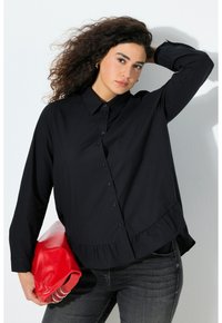 Black long-sleeve shirt with button-down front, ruffled hem, and collar. Model holds a red leather clutch. Worn with dark jeans.
