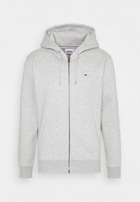 Grauer Zip-Hoodie aus weichem Stoff, mit Kapuze, Fronttaschen und einem kleinen Logo auf der linken Brust. Lässiges Design mit gerippten Bündchen.