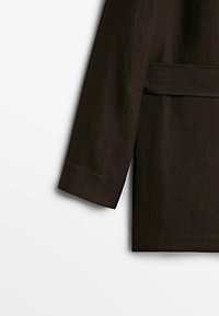 Manche de veste en lin marron présentant une coupe droite et un détail de poche, avec une texture lisse et un ourlet cousu.