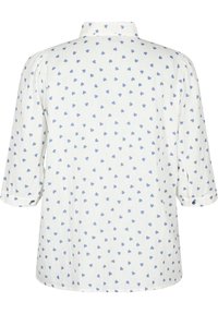 White shirt with light blue heart pattern, three-quarter sleeves, button accents at sleeve cuffs, and a soft linen texture.