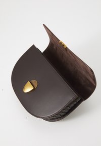 Sac à main en cuir marron, de forme arrondie, avec une fermeture en métal doré et un intérieur en daim doux. Détail tissé sur le côté.