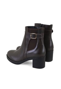 Bottines en cuir marron avec des panneaux latéraux en élastique, un accent en boucle et un talon épais. Texture lisse avec une finition polie.