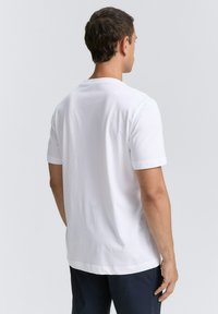 Weißes T-Shirt mit kurzen Ärmeln und Rundhalsausschnitt, mit glatter Textur und leicht abgerundetem Saum. Schlichtes Design ohne Muster oder Akzente.