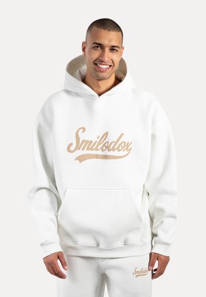 Biała bluza z kapturem z dużym beżowym logo "Smilodox". Posiada kieszeń typu kangur, ściągacze na rękawach oraz wykładany kaptur. Wykonana z miękkiego, pluszowego materiału.