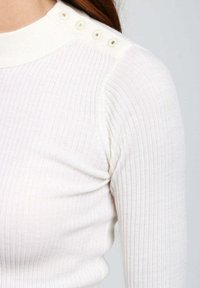 Top lungo a maniche lunghe bianco a coste con scollatura alta e dettagli di bottoni decorativi sulla spalla. Texture morbida e design aderente.