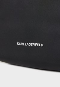 Čierna textúrovaná látková taška s bielym logom "KARL LAGERFELD". Dizajn je jednoduchý, bez ďalších vzorov alebo kovania.