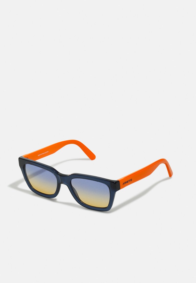 Ruutraamiga päikeseprillid sinise gradient-läbipaistvusega objektiivide, musta plastiku esiosa ja erksate oranžide kätega, millel on graveeritud logo.