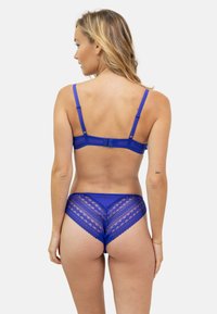 Soutien-gorge bleu avec empiècement en dentelle et culottes assorties, présentant un motif géométrique et des bretelles réglables. Tissu texturé avec une finition lisse.