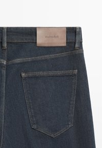 Donkerblauwe spijkerbroeken met aan de achterkant zicht op één achterzak en een bruin leren merkembleem "Massimo Dutti" op de tailleband.