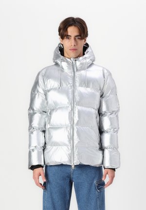 Ezüst színű fújható dzseki fényes, tükröződő felülettel, kapucnival és elülső cipzárral. Kiváltképp kockás mintázattal rendelkezik, látható varrással és textúrával.