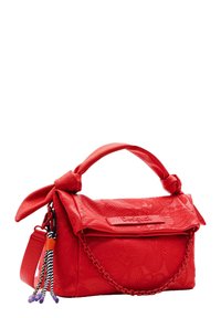 Rote Handtasche aus Kunstleder mit einem strukturierten Blumenmuster, einem geknoteten Griff, Kettenakzenten und bunten Quasten, die an einem Reißverschluss befestigt sind.