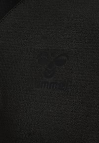 Zwart sportief fabric met een gladde textuur, voorzien van een opvallend reliëflogo van "hummel" in het midden van het kledingstuk.