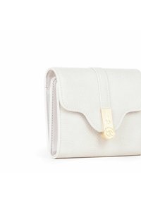 Cartera de cuero texturizado blanco con una solapa con ondulaciones y un cierre de oro que presenta un logo. Diseño compacto con detalles de costura visibles.