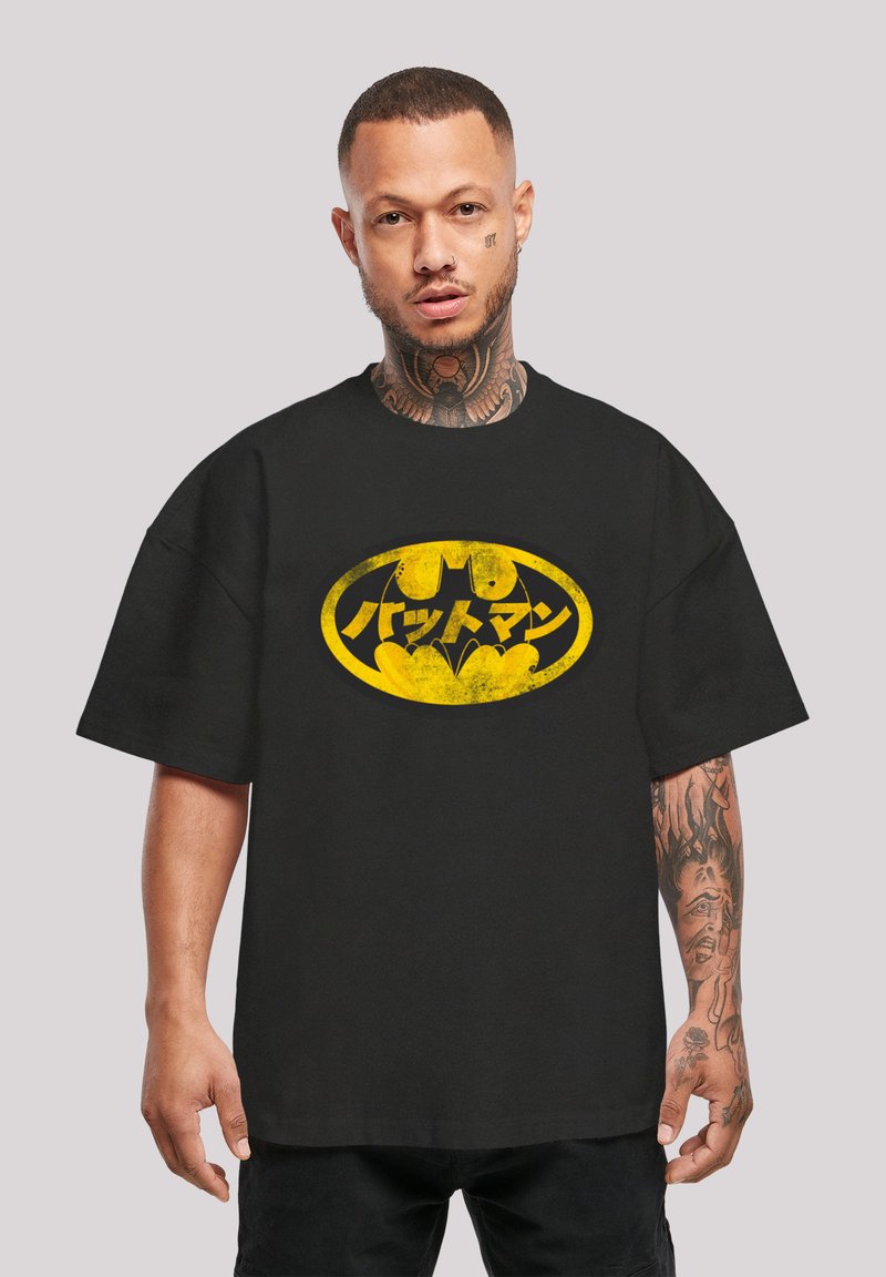 Černé oversized tričko s opotřebeným žlutým logem Batmana a japonským textem, vyrobené z bavlny s krátkými rukávy.