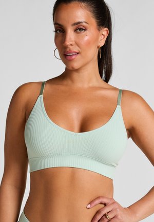 Lichtgroene geribbelde bralette met dunne verstelbare bandjes en een gladde band. Het naadloze ontwerp accentueert de pasvorm en biedt comfort.