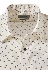 Camicia bianca con motivo floreale nero, taglio moderno. Presenta un colletto classico e un bottone nero sullo scollo. Texture morbida.