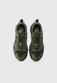 Olivengrønne sneakers med tekstureret mesh og ruskindsmaterialer, der har et toggle snøresystem og gummisåler. Set fra oven.
