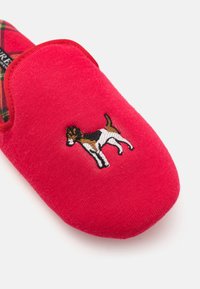 Red fleece slipper with a rounded toe, featuring an embroidered dog design. Inside lined with plaid fabric for added texture.