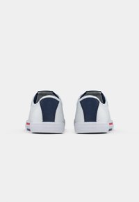 Adidași albi cu accente bleumarin, material texturat și talpă din cauciuc. Prezintă o dungă roz pe călcâi și un guler căptușit.
