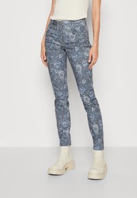 Flerfärgade smala jeans med ett blått och grått paisleymönster, med en medelhög midja och detaljerade framfickor, tillsammans med beige plattformstövlar.