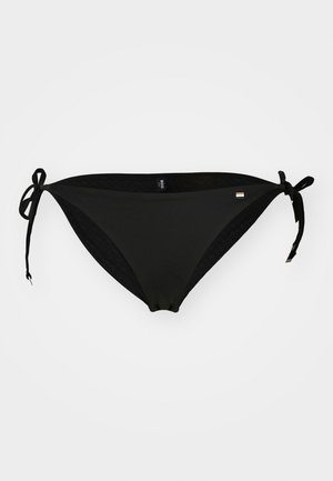 Parte inferiore di bikini nera in un materiale liscio e elasticizzato con lacci ai lati. Caratterizzata da un design minimalista e un'etichetta con logo discreto.