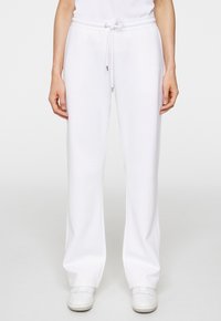 Vita sweatpants av mjukt tyg, med elastiskt midjeband och snörning samt sidoseams. Matcher med vita sneakers.