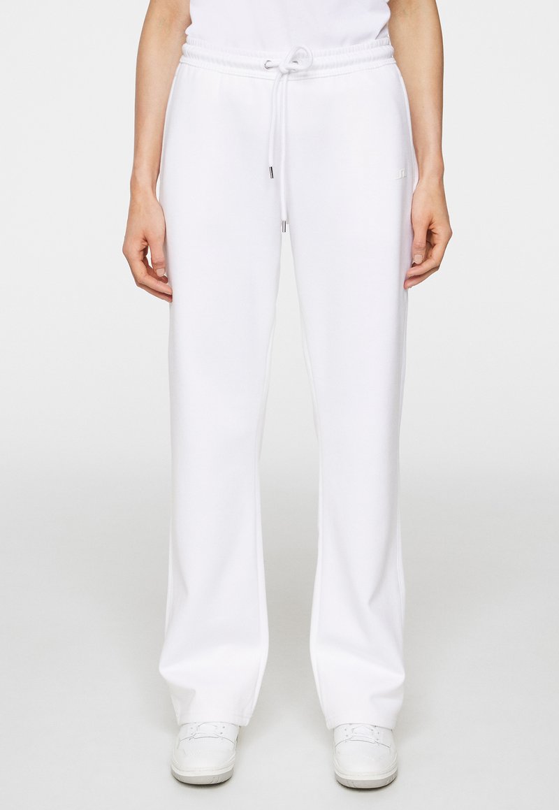 Vita sweatpants av mjukt tyg, med elastiskt midjeband och snörning samt sidoseams. Matcher med vita sneakers.