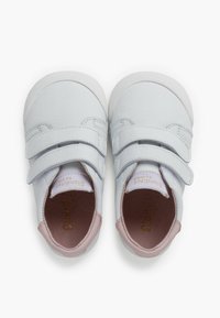 Baskets en cuir blanc avec des accents roses, dotées de deux bandes Velcro, d'une pointe arrondie et d'un intérieur rembourré pour plus de confort. Texture lisse sur l'ensemble.