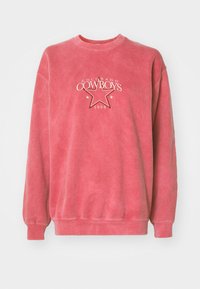 Rosa genser laget av myk stoff med rund hals, med et hvitt "Colorado Cowboys" grafikk og et stjernedesign.