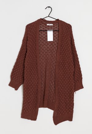 Cardigan en maille marron texturé à manches longues accroché sur un cintre noir sur fond blanc.