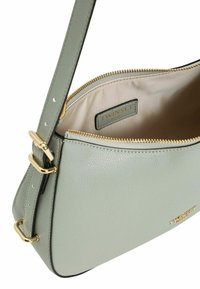 Borsa a spalla in pelle verde chiaro con superficie testurizzata, hardware dorato, chiusura con zip e interno beige con etichetta del brand.