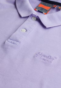 Lila polo shirt van textuurstof met een knoopsluiting en geborduurd logo in bijpassend lila.