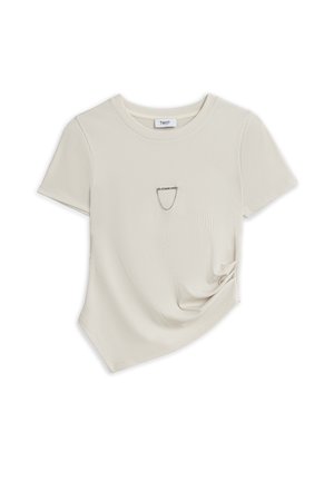 Haut court côtelé à manches courtes de couleur crème avec col rond et un petit détail d'épingle de sûreté près de la poitrine sur fond blanc.