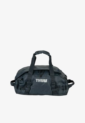 Sac polochon noir Thule avec doubles poignées supérieures, sangles réglables, compartiments zippés et poches latérales.